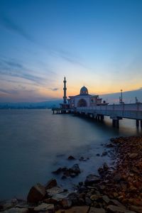 Bridge over sea against sky during sunset