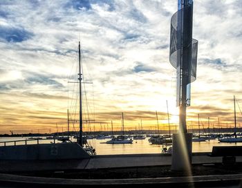 Boats moored at harbor against sky during sunset