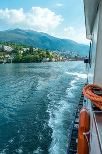 Boat sailing on sea by mountains against sky