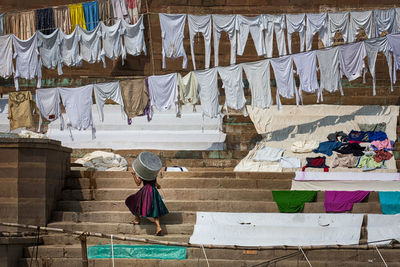 Woman with container walking against clothes on steps