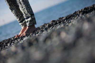 Low section of woman standing on pebbles at beach