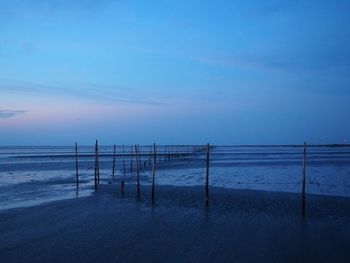 Wooden posts on beach against blue sky