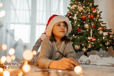 New year's and christmas. a teenage girl in a santa claus hat writes a letter to santa claus 