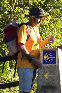 Man holding stone while standing on field against tree