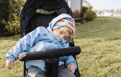 Cute boy sleeping on baby stroller at lawn