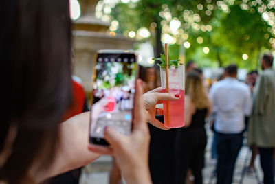 Selective focus image of woman taking photo of her cocktail.