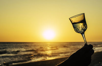 Romantic glass of wine on the beach at orange sky and sun, sunset glasses of white wine