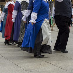 Low section of people walking on street in city