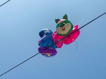 Low angle view of toys on cable against clear sky