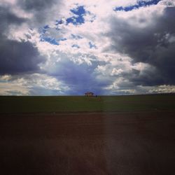 Scenic view of field against cloudy sky