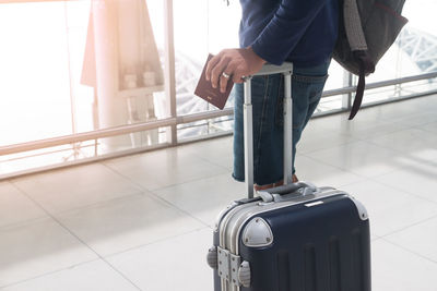 Midsection of man standing with suitcase