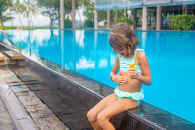 Side view of woman drinking water while sitting on railing