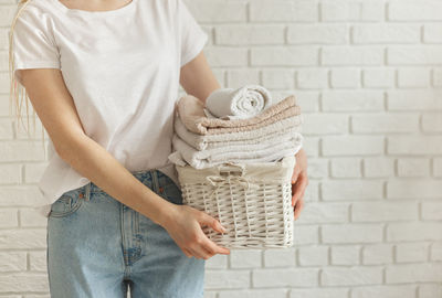Midsection of woman holding basket against wall