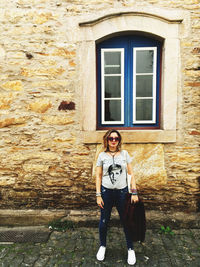 Full length of young woman standing against building