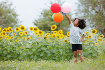 Rear view of woman holding red balloons on field