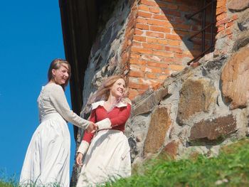 Smiling two women standing against brick wall