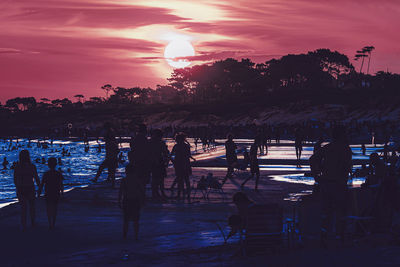 Silhouette people at beach against sky during sunset