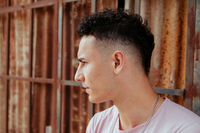 Close-up of young man by corrugated iron