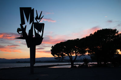 Silhouette trees by sea against sky during sunset