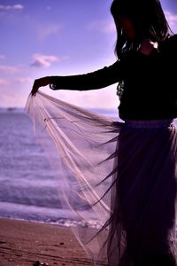 Woman standing on beach against sky during sunset