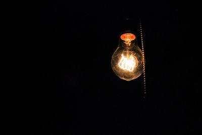 Close-up of illuminated light bulb against black background