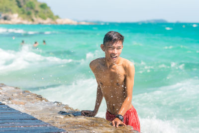 Portrait of shirtless man standing at beach