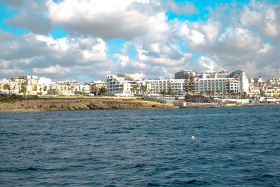 Scenic view of sea by buildings against sky