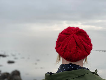 Rear view of woman with red knit hat against sky