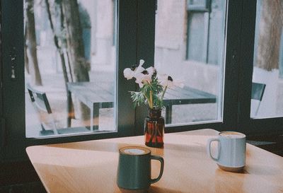 Flower vase on table by window