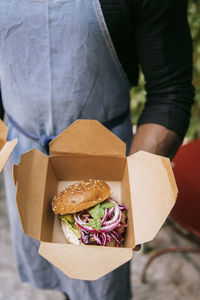 High angle view of male restaurant owner holding freshly prepared burger in box