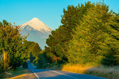 Road amidst trees and mountains against sky