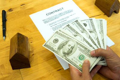 High angle view of hand holding paper on table