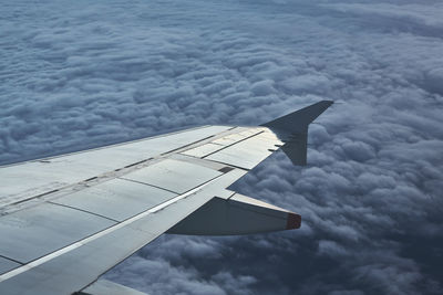 Cropped image of aircraft wing flying against sky