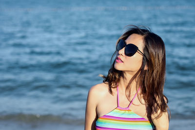 Woman wearing sunglasses standing against water