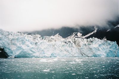 Scenic view of glacier by sea against sky