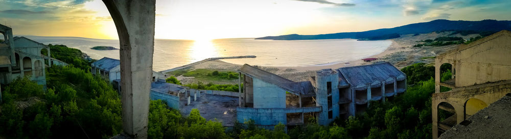 Panoramic view of sea and buildings against sky during sunset