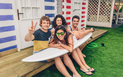 Portrait of smiling young friends with surfboard