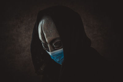 Portrait of person wearing mask against black background