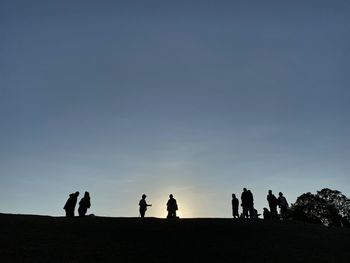 Silhouette people against clear sky during sunset