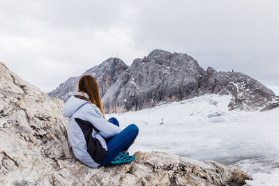 Young millennial girl enjoys the views of the alps standing on glacier