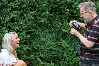 Man and woman holding umbrella while standing by plants