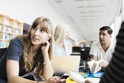 Young woman with friends studying in university library