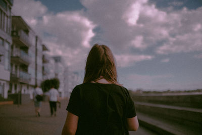 Rear view of woman standing against sky during sunset
