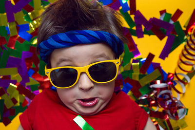 Child a boy in a red t shirt and sunglasses is lying on yellow paper resting at home