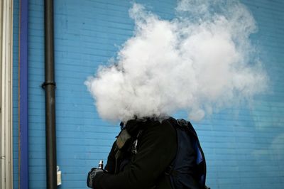 Midsection of man smoking hookah against blue wall