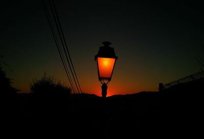 Low angle view of illuminated lamp at sunset