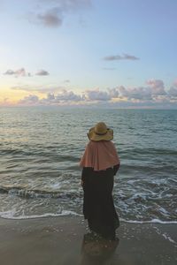 Rear view of woman standing on beach during sunset