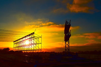 Low angle view of silhouette cranes against sky during sunset