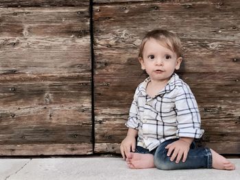 Portrait of cute boy sitting on wood