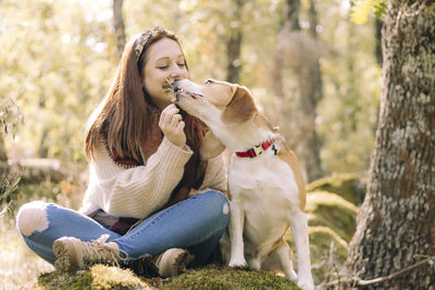 Smiling young woman, sitting next to her dog during a walk